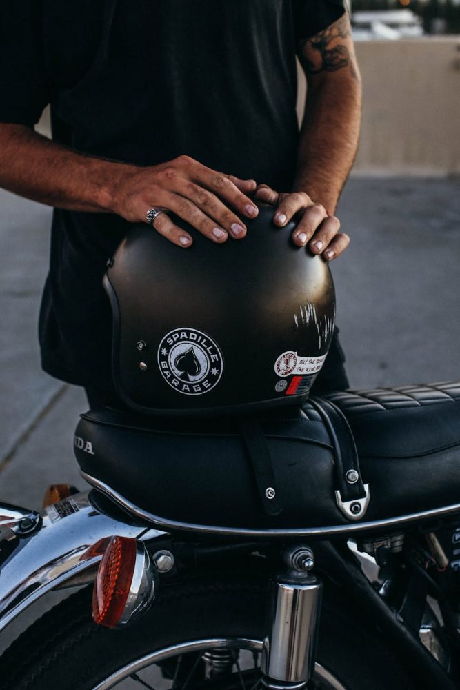crop ethnic man near motorbike with helmet
